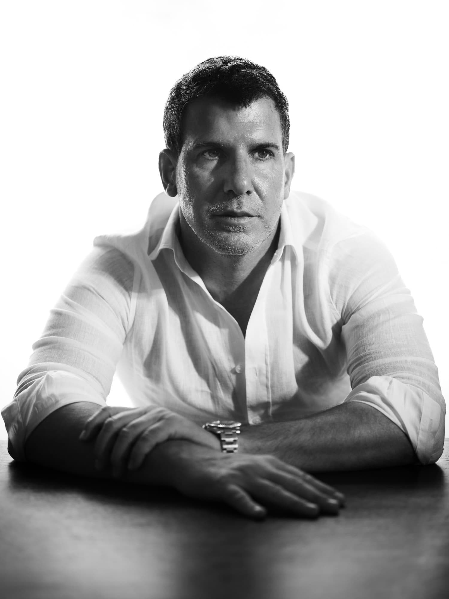 studio portrait in palma, man in white shirt leaning on table, soft contrast